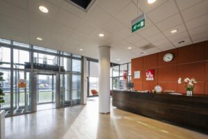 Receptiebalie van IBFD in de entreehal van het gebouw Rietlandpark met zicht op de glazen draaideur en wachtruimte.