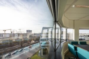 Vergaderruimte met uitzicht op Rietlandpark, modern stadsverkeer en bouwwerkzaamheden met hijskranen.