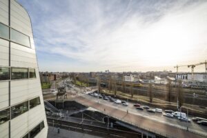Uitzicht op Rietlandpark in Amsterdam met een drukke weg, spoorlijn, passerende trein en omliggende bebouwing.