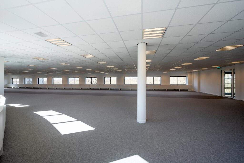 Ruim, leeg kantoorpand aan de Wegalaan met systeemplafond, tapijtvloer en meerdere ramen.