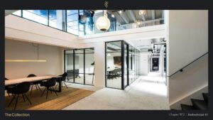 Modern office interior at Stadhouderskade 85 featuring glass meeting rooms, a long wooden table, and contemporary lighting.