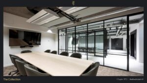 Modern conference room at Stadhouderskade 85 with glass walls, a large wooden table, and a wall-mounted screen.