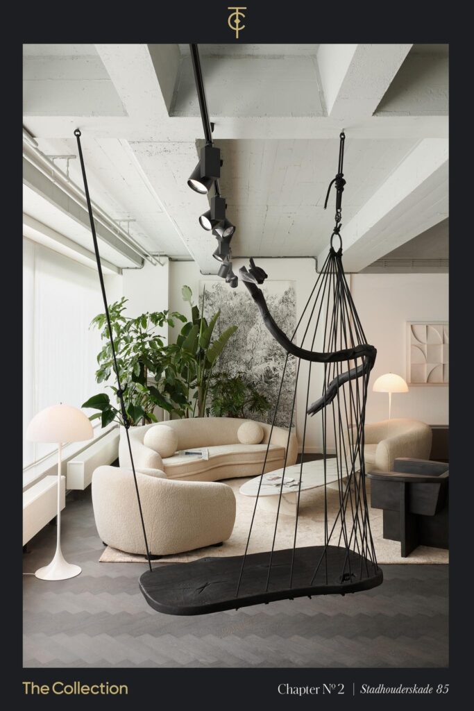 Modern living room interior at Stadhouderskade 85 featuring a sculptural black swing, curved cream sofas, and minimalist decor with abundant natural light.