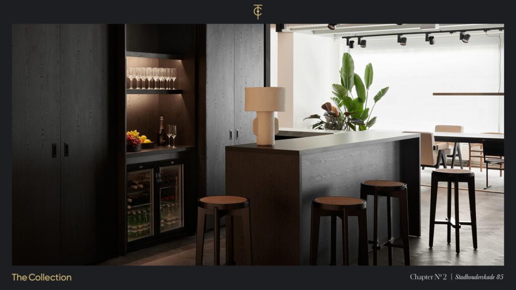 Modern lounge area with a dark wooden bar, stools, and built-in beverage cabinet at Stadhouderskade 85.