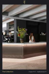 Modern reception area at Stadhouderskade 85 with a marble counter, floral arrangement, and a woman working on a laptop.