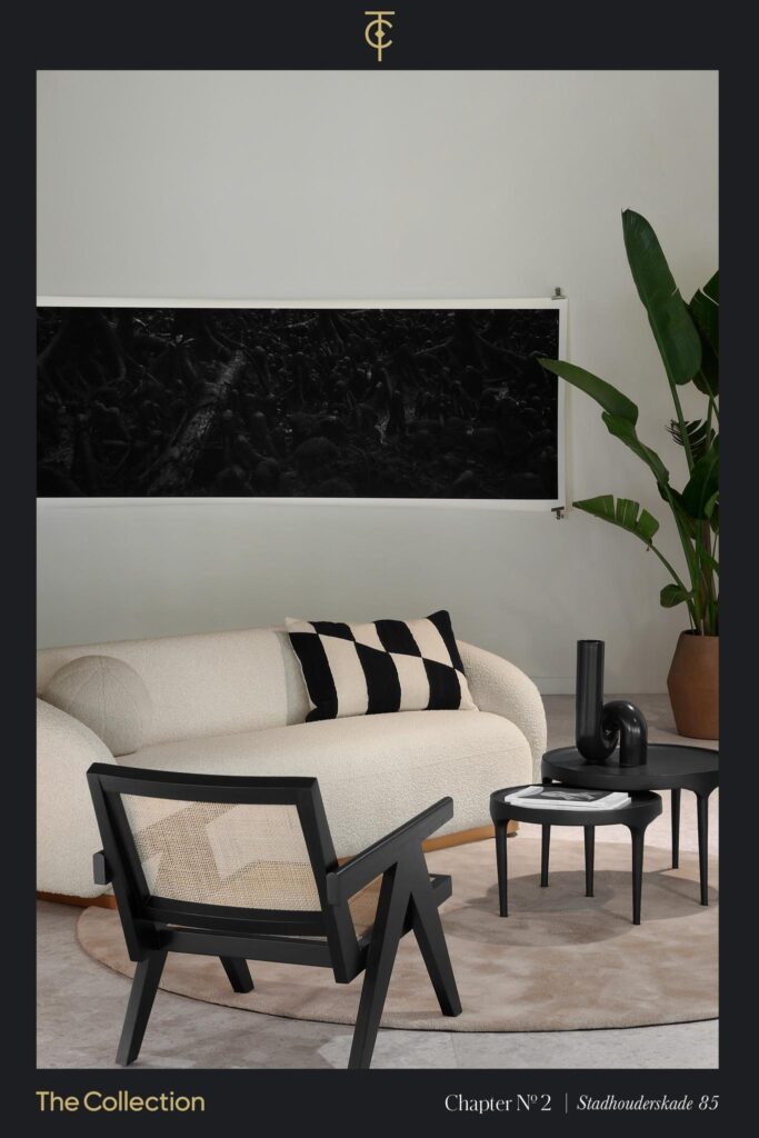 Modern interior with a cream sofa, black accent chair and decor, a large plant, and monochrome artwork at Stadhouderskade 85.