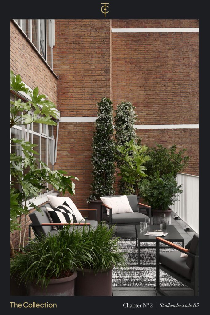 Modern outdoor seating area on a terrace at Stadhouderskade 85, surrounded by lush potted plants and brick walls.