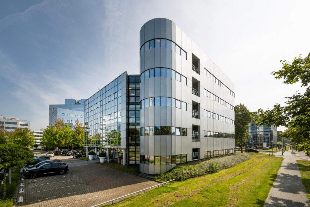 Modern kantoorpand aan de Hogehilweg in Amsterdam met spiegelende gevel en omliggende parkeerruimte.