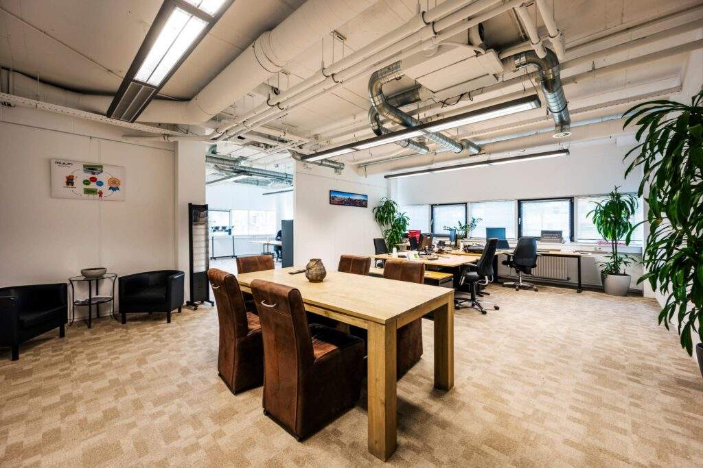Modern kantoorinterieur aan de Hogehilweg met open werkplekken, vergadertafel en veel daglicht.