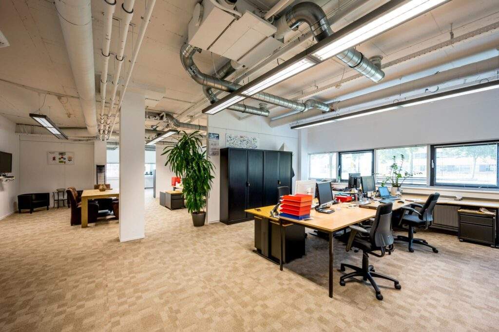 Ruim en modern kantoorinterieur aan de Hogehilweg met bureaus, stoelen, planten en kasten.