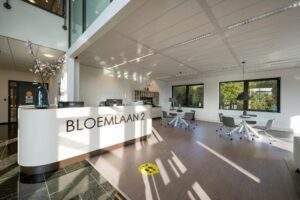 Moderne en lichte ontvangsthal met balie en zitgedeelte aan de Bloemlaan 2.