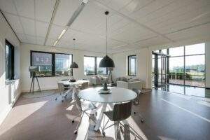 Moderne en lichte kantoorruimte aan de Bloemlaan met ronde vergadertafels, zithoeken en grote ramen.