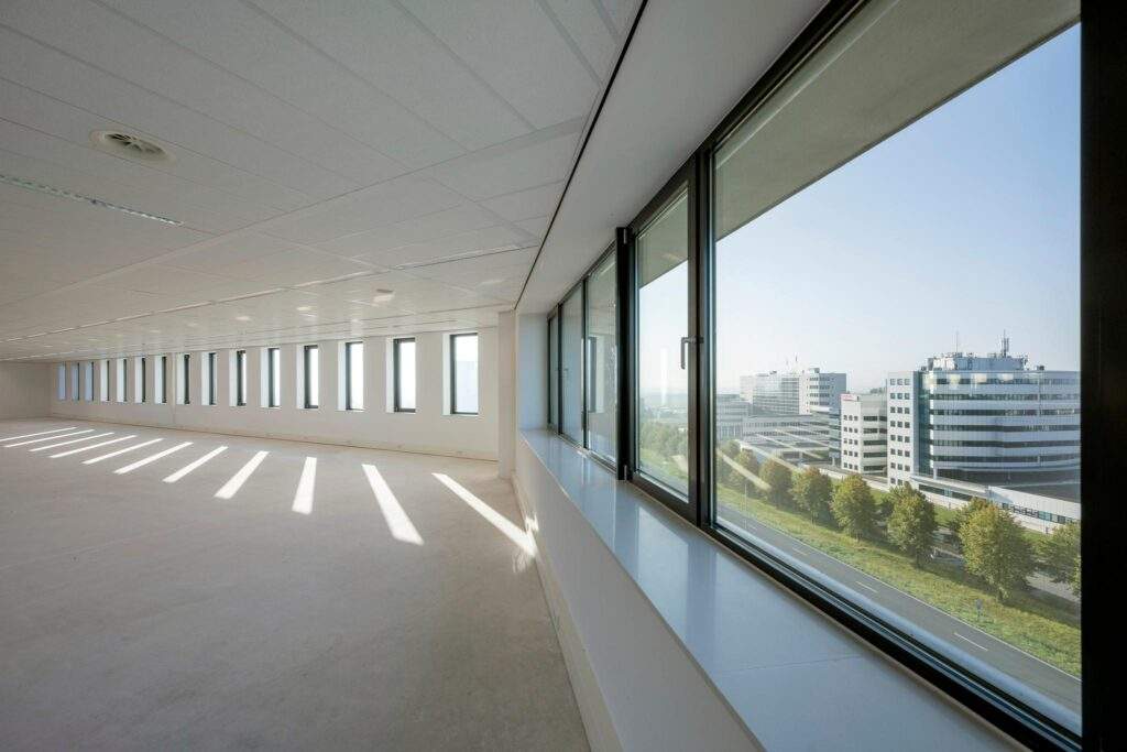 Leeg kantoorpand aan de Bloemlaan met uitzicht op moderne kantoorgebouwen en een groene laan.