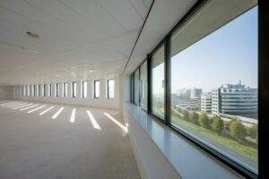 Leeg kantoorpand aan de Bloemlaan met uitzicht op moderne kantoorgebouwen en een groene laan.