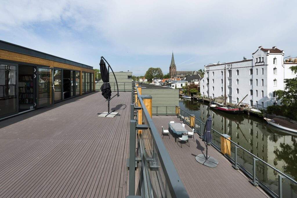 Ruim dakterras aan de Nieuwendammerkade met uitzicht op een gracht, historische panden en een kerktoren in de verte.