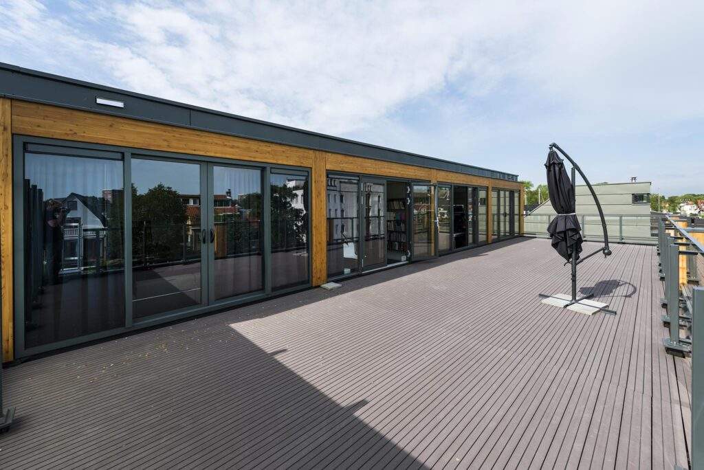 Ruim dakterras aan de Nieuwendammerkade met houten gevelbekleding, glazen schuifdeuren en een gesloten parasol.