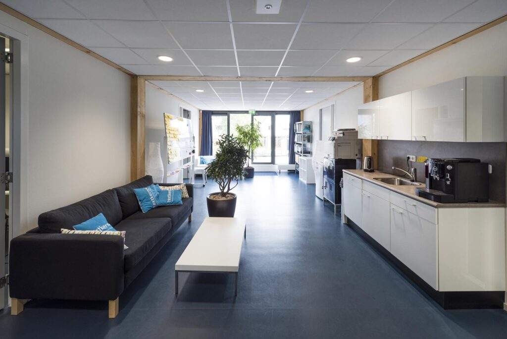 Moderne, lichte kantoorlounge aan de Nieuwendammerkade met een zithoek, keuken en grote ramen.