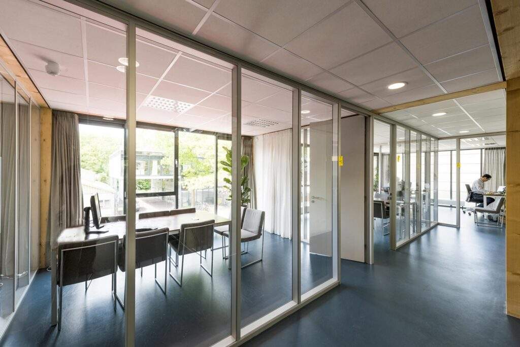 Moderne kantoorruimte aan de Nieuwendammerkade met glazen vergaderruimtes en werkplekken met natuurlijk licht.