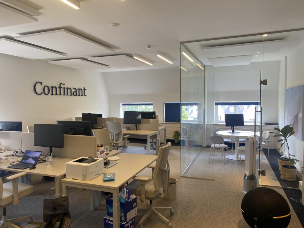 Modern kantoorinterieur van Confinant aan de Herengracht met werkplekken en een glazen vergaderruimte.