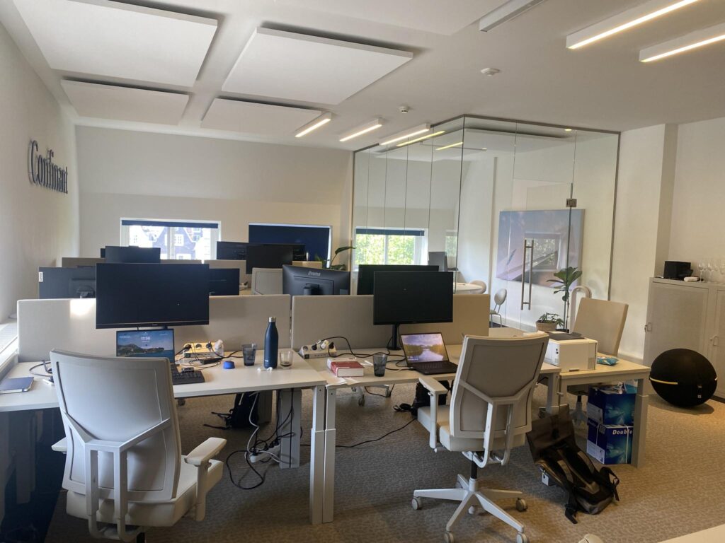 Modern kantoorinterieur aan de Herengracht met meerdere werkplekken, bureaustoelen en computerschermen.