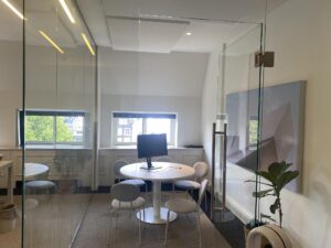 Vergaderruimte aan de Herengracht met ronde tafel, stoelen, computerscherm en glazen wanden.
