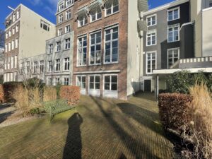 Binnenplaats met groen, een bankje en de achtergevels van appartementen aan de Herengracht in Amsterdam.