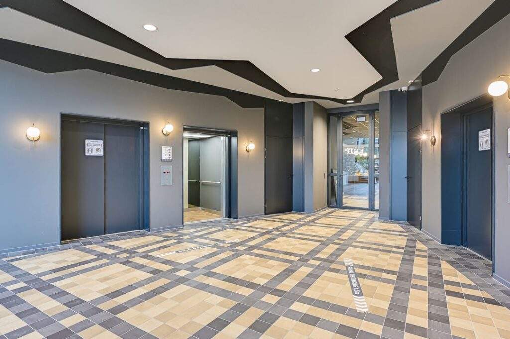 Moderne liftlobby aan de Kingsfordweg met drie liften, opvallend tegelpatroon en glazen ingang naar kantoorruimte.