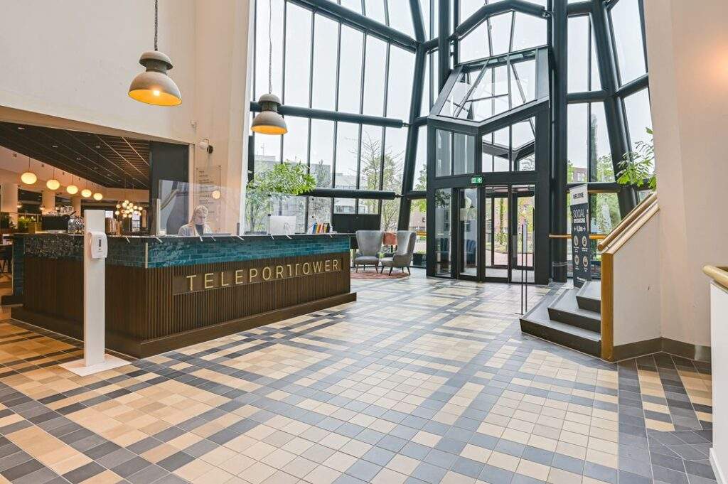 Ingang en receptie van het kantoorgebouw Teleport Tower aan de Kingsfordweg, met hoge glazen gevel en moderne inrichting.