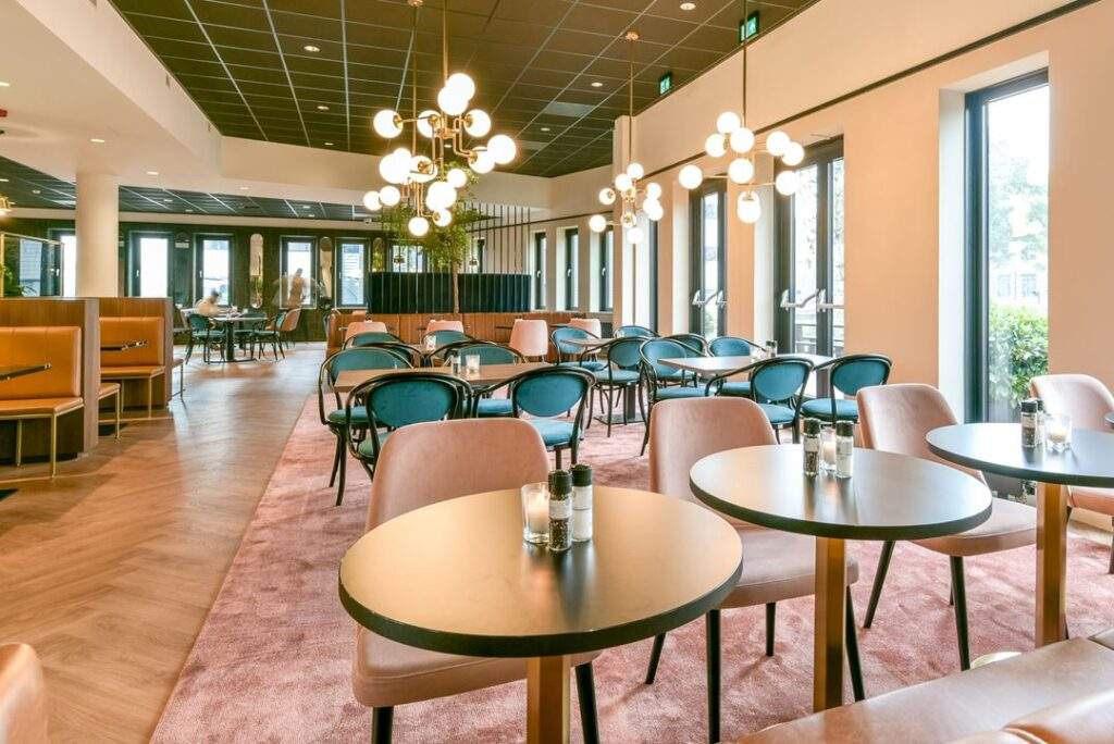 Modern ingerichte eetruimte aan de Kingsfordweg met stijlvolle zitplaatsen, ronde tafels en sfeervolle verlichting.