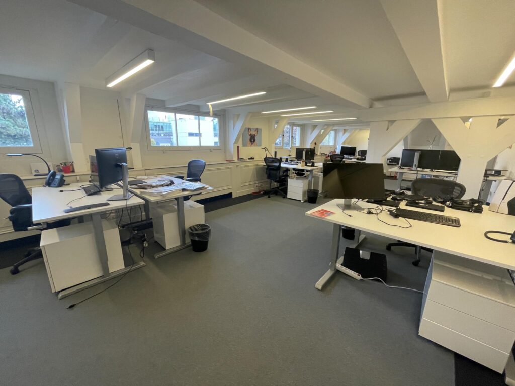 Modern open-plan office space with multiple desks, computers, and ergonomic chairs on the Herengracht.