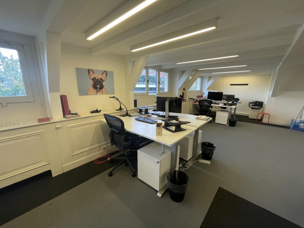 Modern office space on Herengracht with desks, computers, and a large wall photo of a French bulldog.