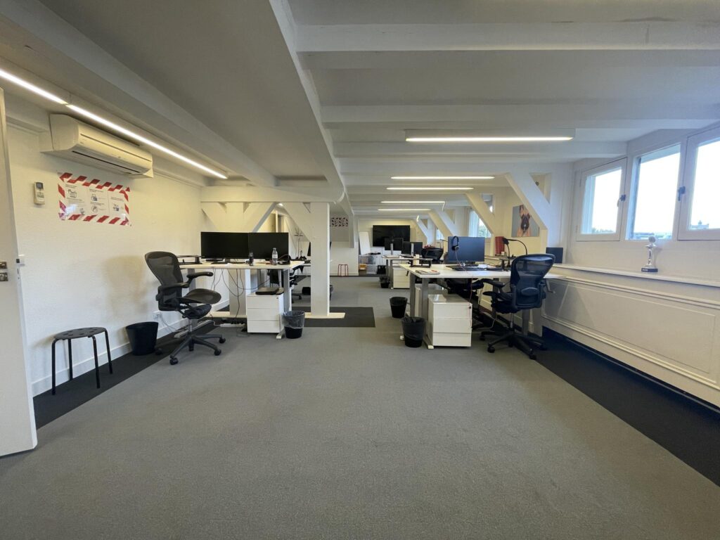 Modern open-plan office space on the Herengracht with several desks, office chairs, and computer monitors.