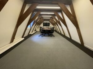 Conference room in a Herengracht attic space with wooden beams, a long table, and office chairs.