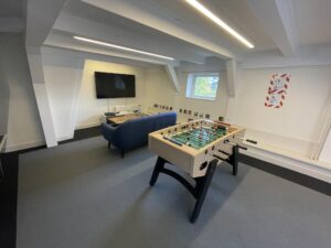 Modern recreational room with a foosball table, a blue couch, and a wall-mounted TV on Herengracht.
