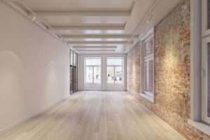 Licht en modern interieur met houten vloer, bakstenen muur en grote ramen aan het Rokin.
