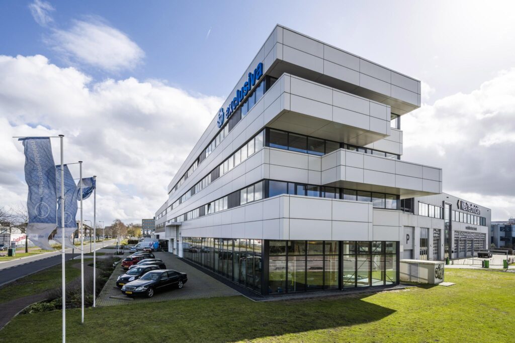 Modern kantoorpand van Exclusiva aan de Dynamostraat met parkeergelegenheid en vlaggenmast op de voorgrond.