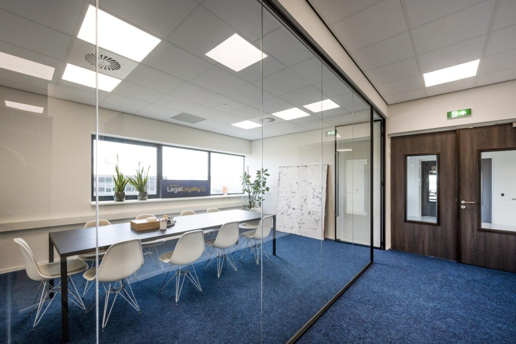 Vergaderruimte van notariskantoor LegalLoyalty met een lange tafel, witte stoelen en glazen wanden.