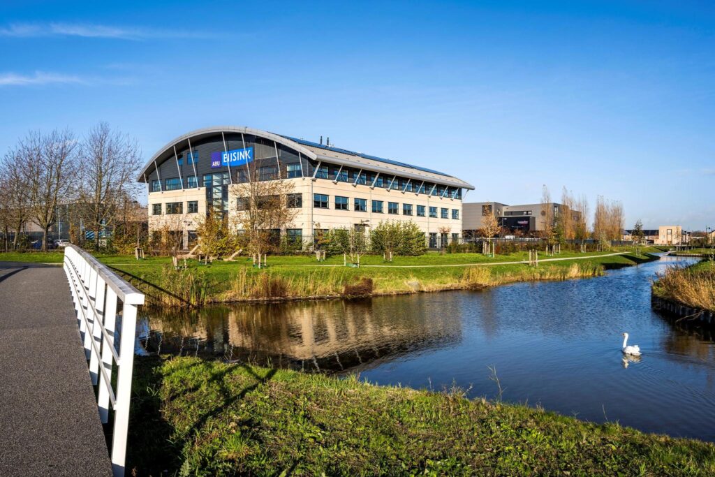 Kantoorpand van Eijsink aan de Singaporestraat in een groene omgeving met water en een zwaan op de voorgrond.