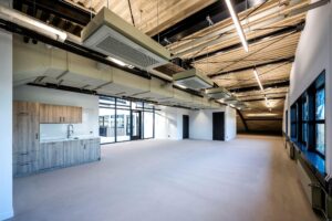 Modern, industrieel afgewerkte kantoorruimte aan de Singaporestraat met open indeling, kitchenette en zichtbare ventilatiekanalen.