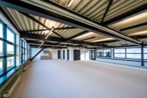 Licht en modern kantoorinterieur aan de Singaporestraat met open ruimte, grote ramen en industriële plafondconstructie.
