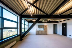 Modern industrieel kantoorinterieur aan de Singaporestraat met grote ramen, zichtbare plafondconstructie en kitchenette.