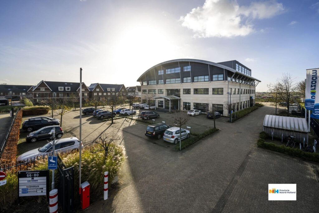 Kantoorpand aan de Singaporestraat in een bedrijventerrein met parkeerplaatsen en woonhuizen op de achtergrond.