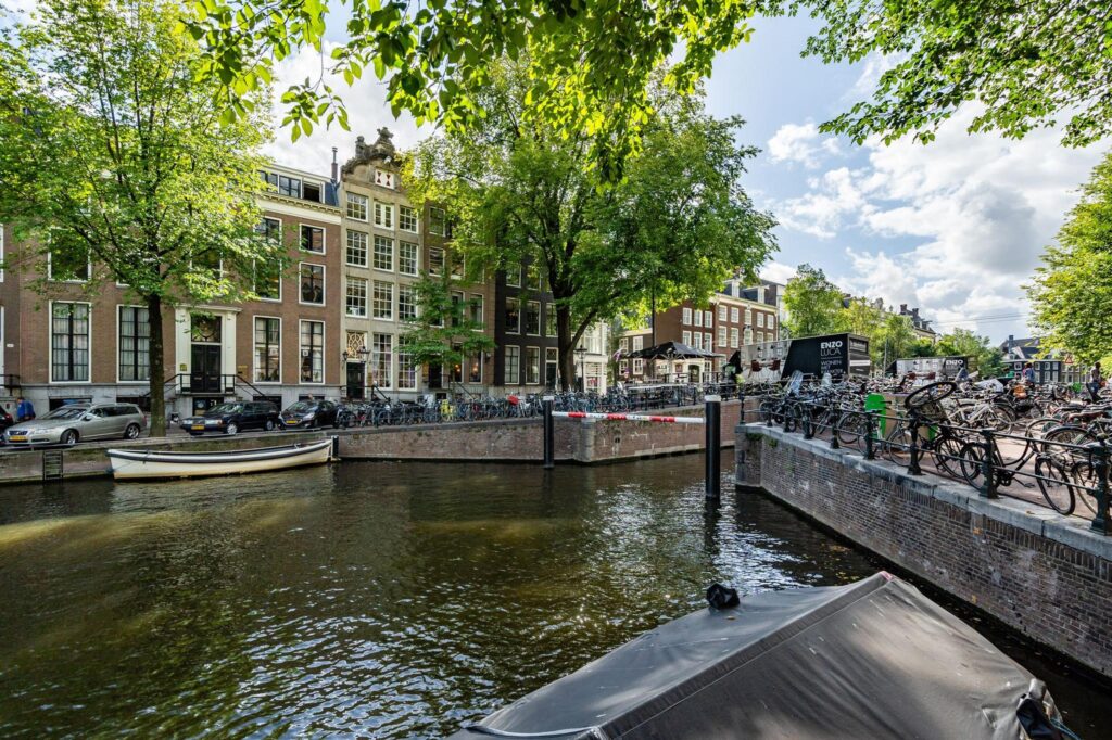 Zonnige gracht in Amsterdam met klassieke herenhuizen, fietsen en een aanlegsteiger bij Herengracht.
