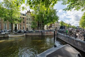 Zonnige gracht in Amsterdam met klassieke herenhuizen, fietsen en een aanlegsteiger bij Herengracht.