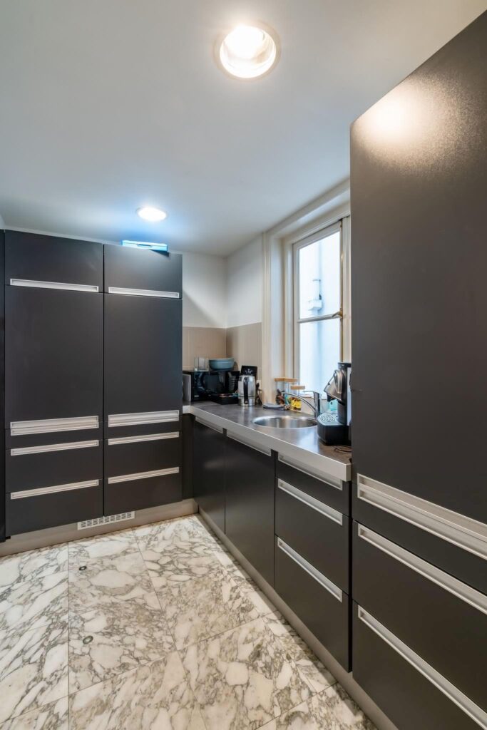 Moderne keuken met donkergrijze kasten, marmeren vloer en een roestvrijstalen aanrechtblad aan de Herengracht.