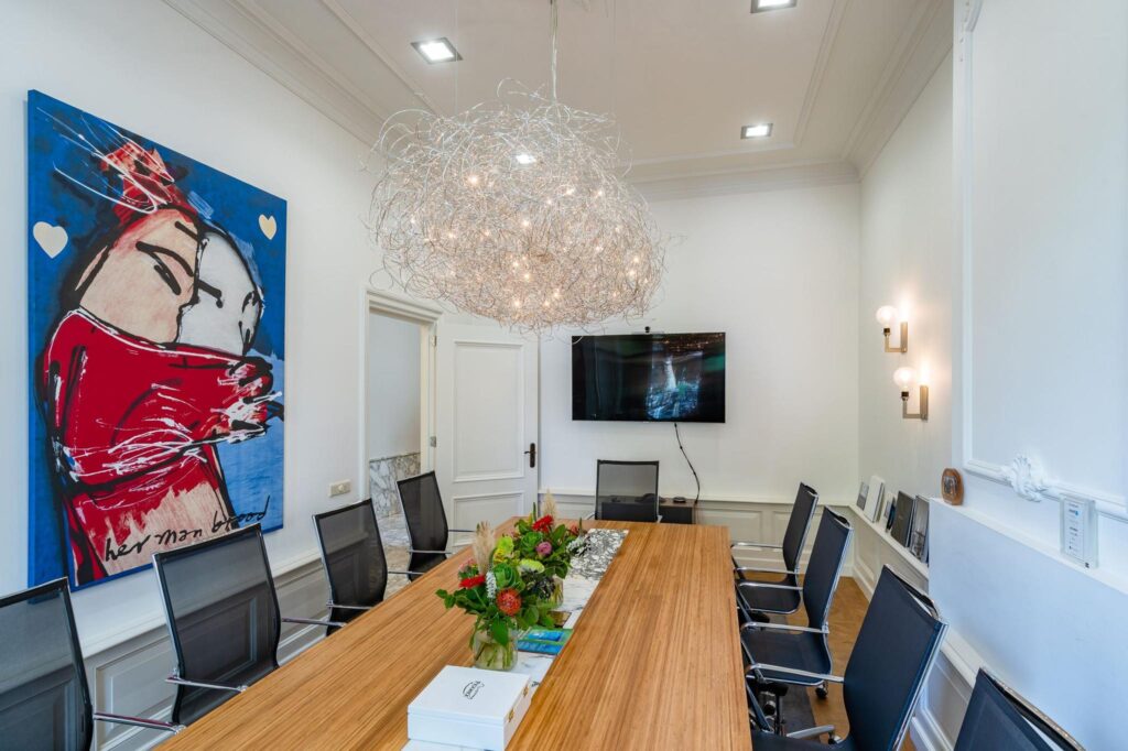 Vergaderruimte aan de Herengracht met moderne inrichting, opvallend kunstwerk en sierlijke lichtinstallatie.
