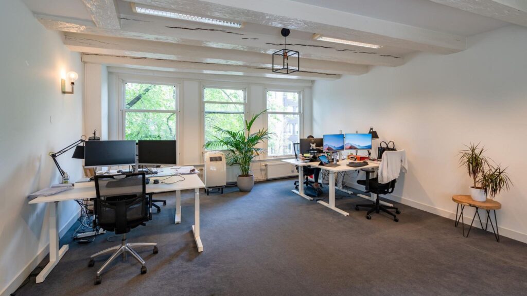 Licht en modern kantoor aan de Herengracht met werkplekken, grote ramen en planten.