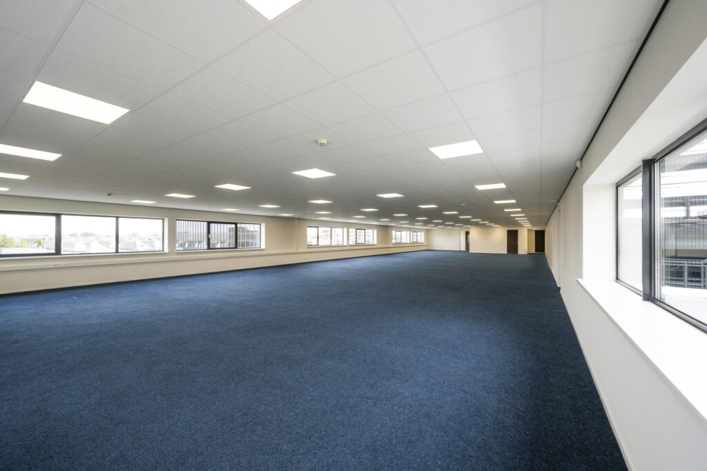 Spacious, empty office floor with blue carpet and large windows on Dynamostraat.