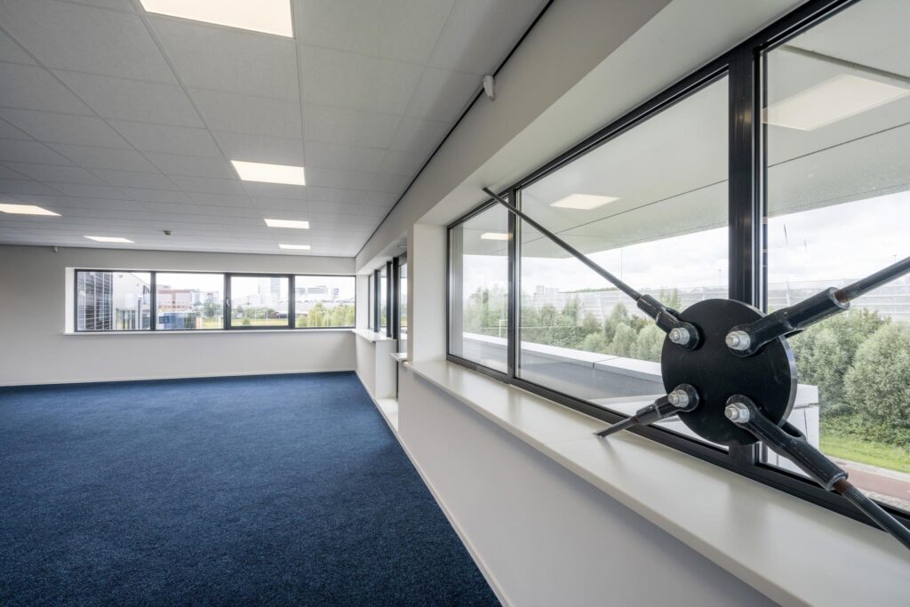 Modern empty office space with large windows and blue carpet on Dynamostraat.