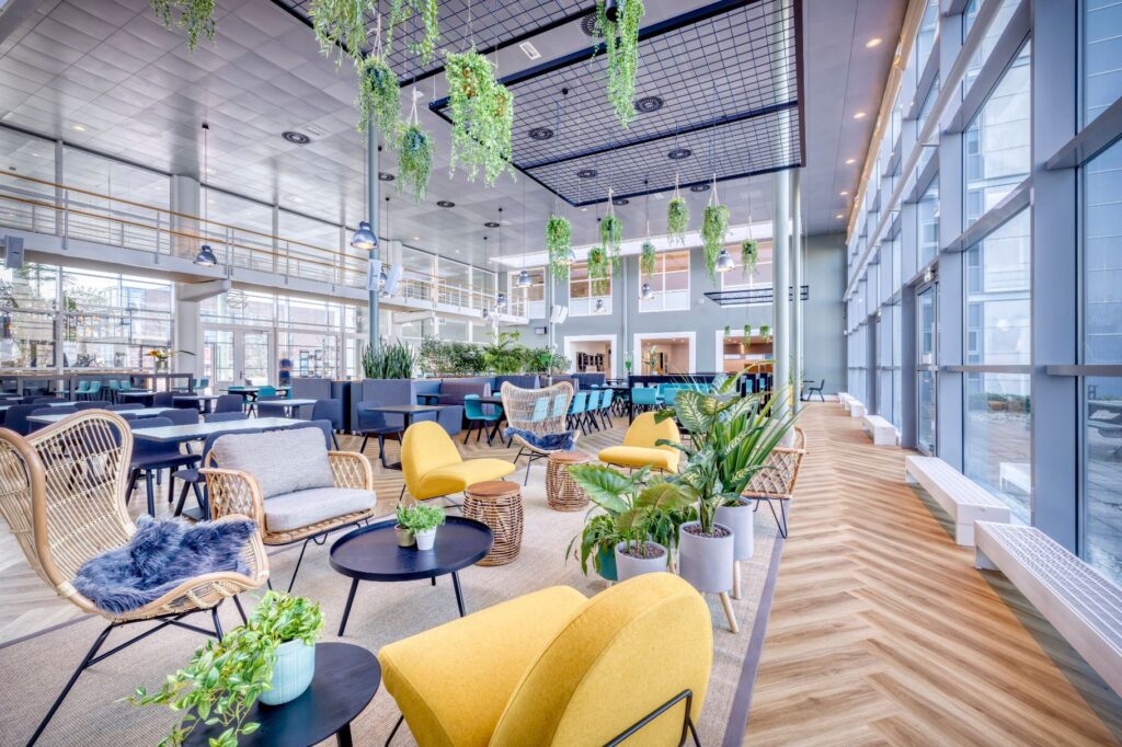 Moderne en lichte lounge- en werkruimte aan de Spicalaan met comfortabele zitplekken, hangplanten en veel glas.